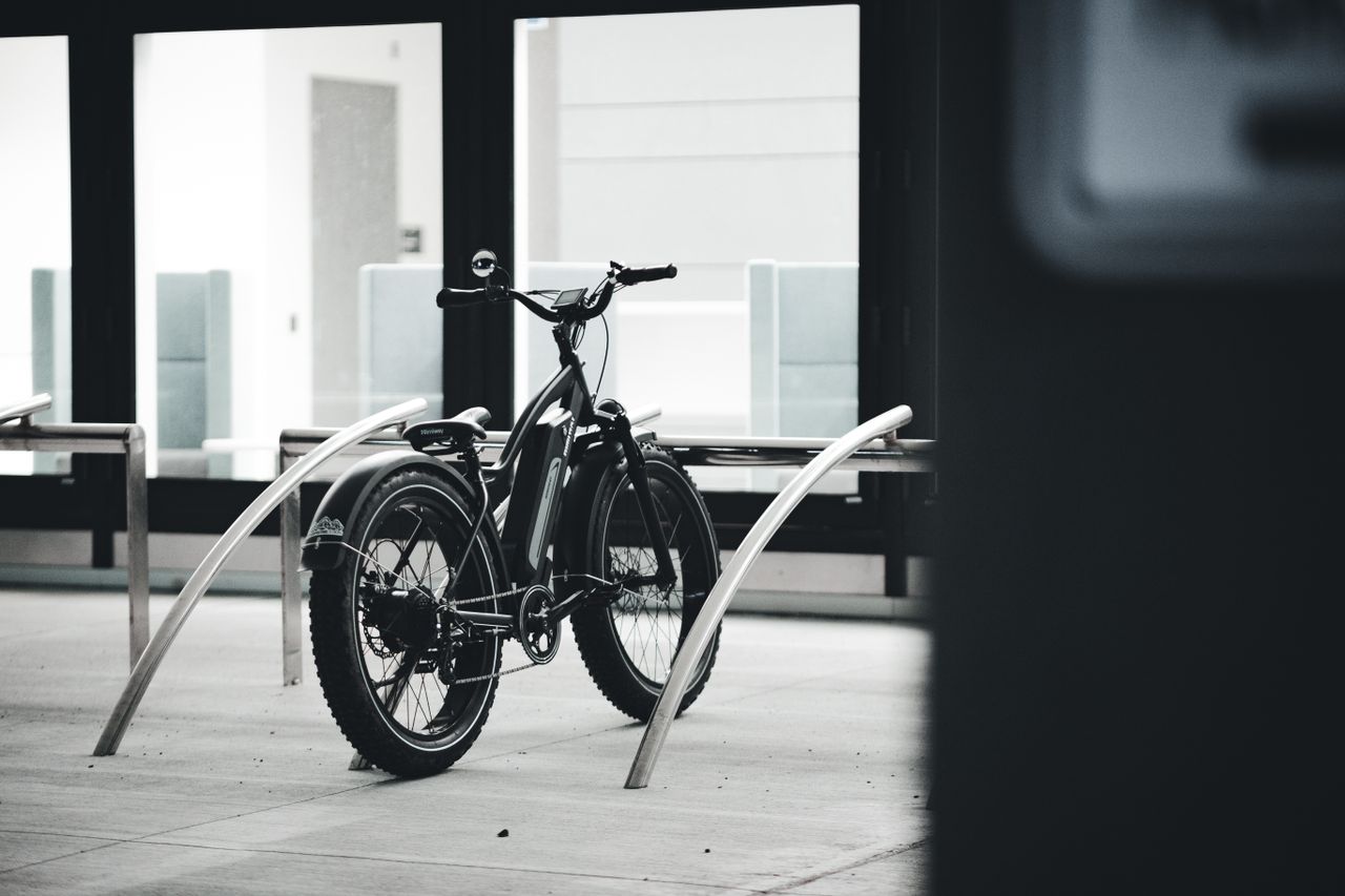Black and white image of an electric bicycle parked indoors in an urban environment.